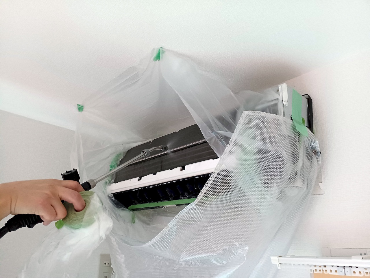 周囲を養生してエアコン内部を洗浄する作業